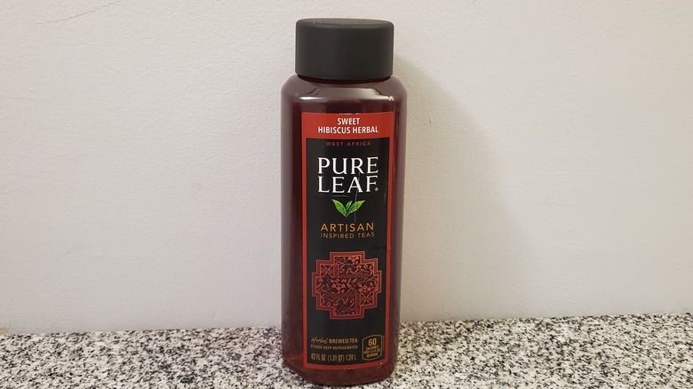 A bottle of Pure Leaf Sweet Hibiscus Herbal Tea on black and grey granite counter